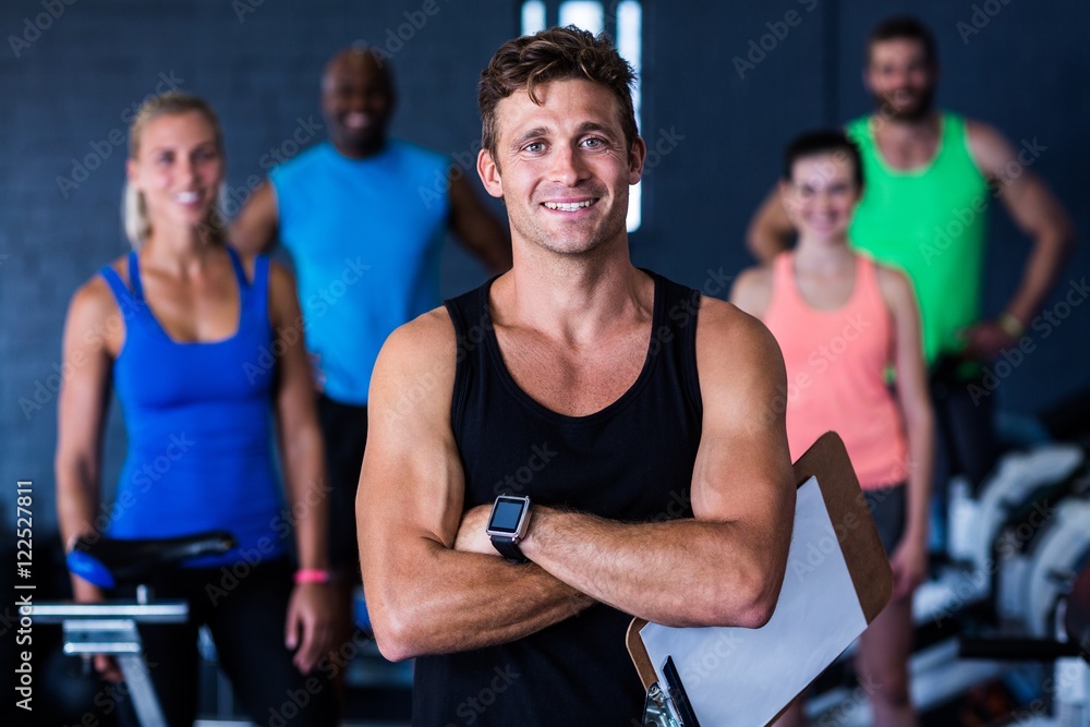 Portrait of smiling gym trainer holding clipboard 