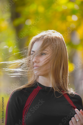 Portrait of Young attractive female at workout in autumn park - waving blond hair