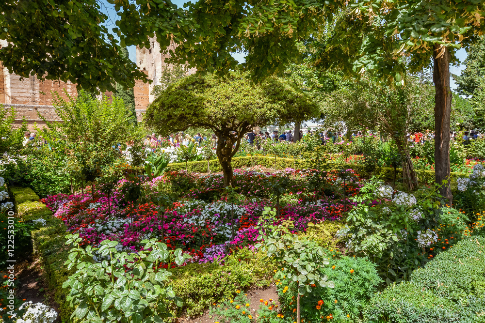 View of the beautiful garden in Alhambra complex and a queue of people waiting for entering the Nasrid Palaces, Granada, Spain View of the beautiful garden in Alhambra complex and a queue of people waiting for entering the Nasrid Palaces, Granada, Spain