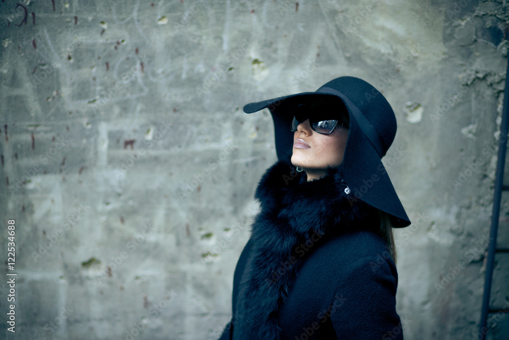 Portrait of mysterious woman hidden in black coat and hat
