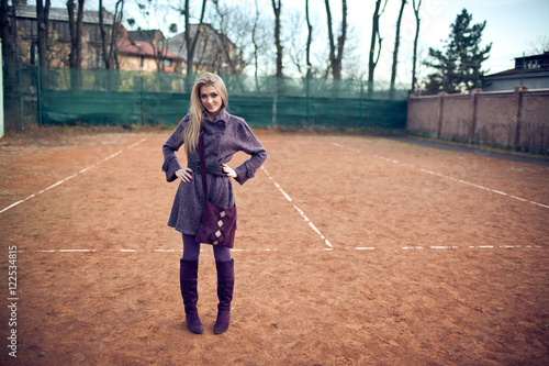 Charming blonde dressed in violet stands on the empty court