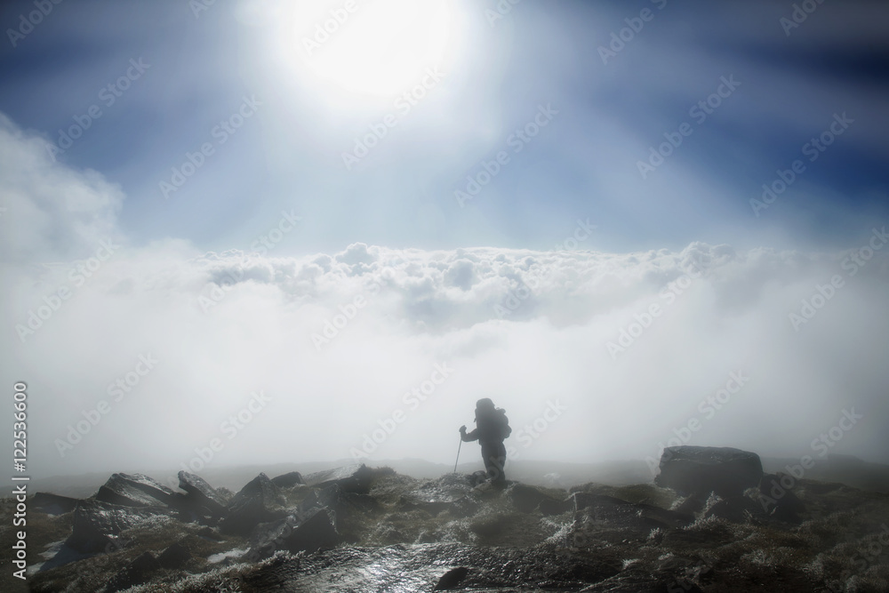 Mountaineer reaches the top of mountain in fog and autumn morning sun Mountaineer reaches the top of mountain in fog and autumn morning sun