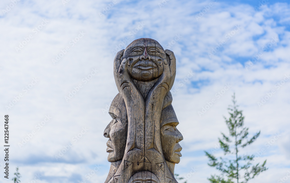 A wooden totem pole in British Columbia Canada at blue sky backg A wooden totem pole in British Columbia Canada at blue sky backg