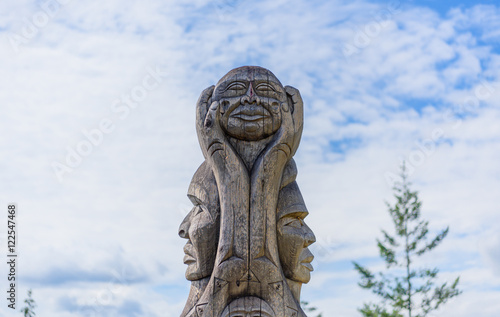 A wooden totem pole in British Columbia Canada at blue sky backg