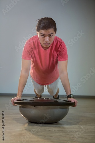 Man doing push-up on bosuball photo