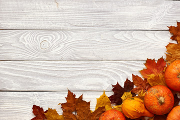 Autumn leaves and pumpkins over old wooden background