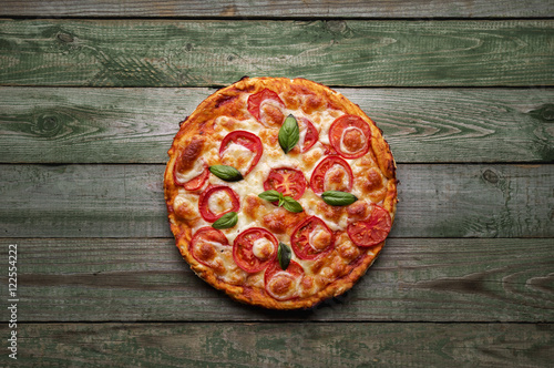 Delicious pizza with cheese and tomatoes on rustic wood table