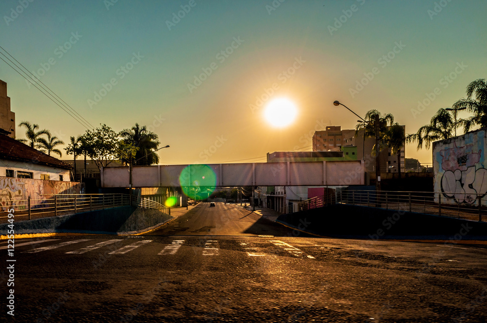 Empty street with a pedestrian walkway over the street in a beautiful sunset landscape 