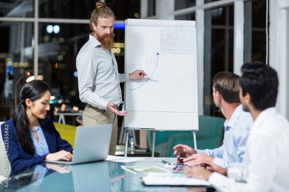 Obraz premium Businessman discussing graph on white board with colleagues