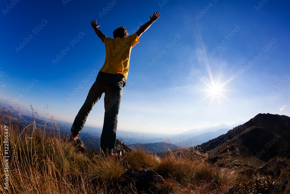 Concept: freedom. A man standing at mountain top with open arms Concept: freedom. A man standing at mountain top with open arms