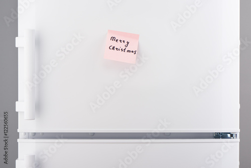 Merry Christmas note on pink sticky paper on white refrigerator