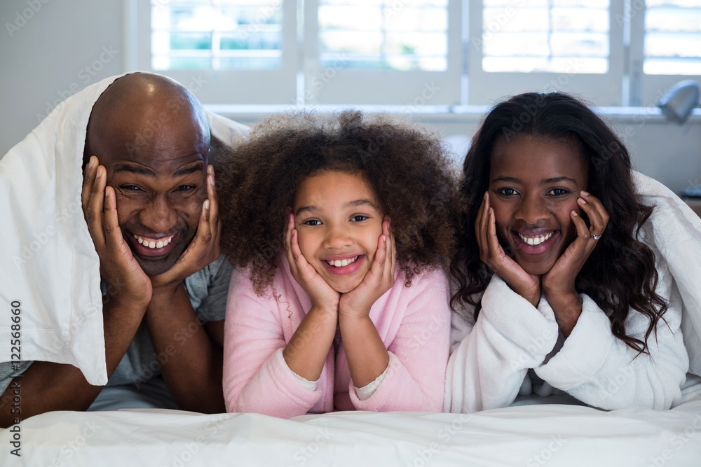 Obraz premium Family with hands on face lying on bed