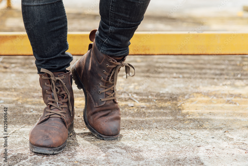 Men fashion, man's legs in black jeans and brown leather boots.