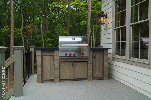 Gas grill on deck with trees in background 
 photo