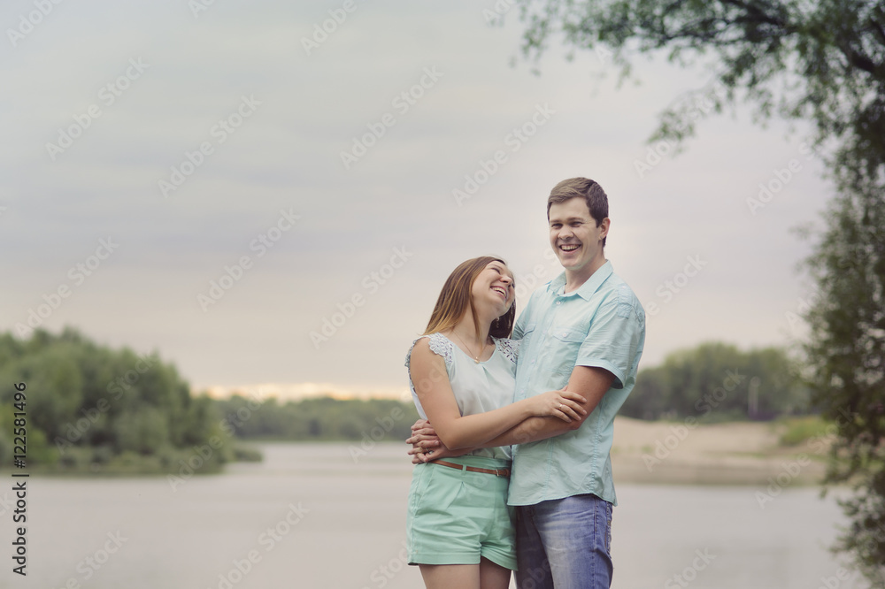Lovers man and woman standing on the river Bank laugh and have fun, turquoise clothes. Lovers man and woman standing on the river Bank laugh and have fun, turquoise clothes.