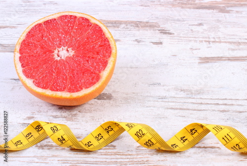 Fresh ripe grapefruit and centimeter on old wooden background