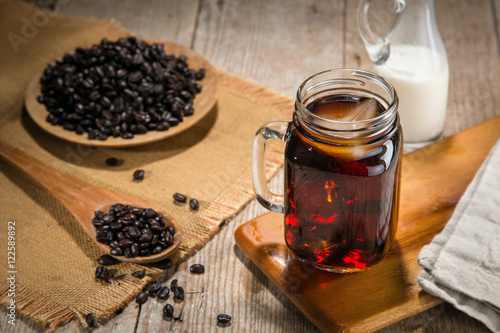 Artisan iced coffee in a jar with rustic stylized decor wooden table coffee beans