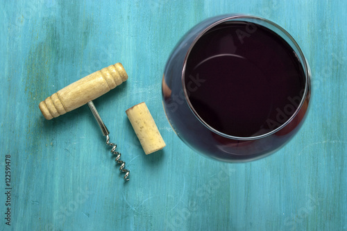 Glass of red wine and corkscrew with cork