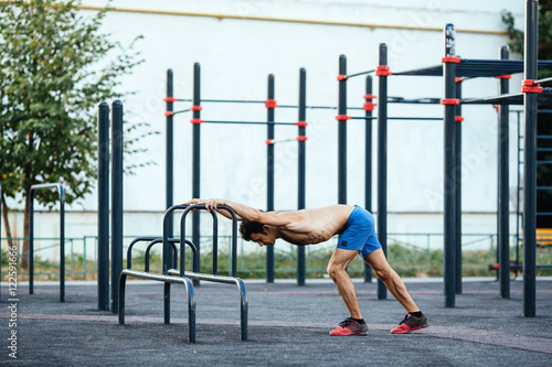 Muscular man warming up before exercise at crossfit ground doing push ups as part of training. Sport concept