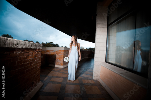 Lonely bride walks along the brick balcony