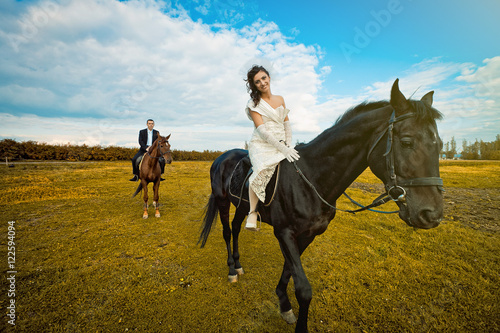 Look from below at beautiful brunette woman riding black horse w