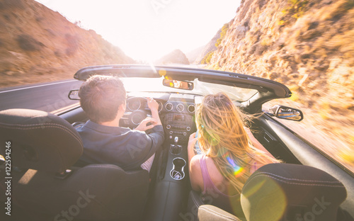 Couple driving fast on a sport convertible car in the canyons. 