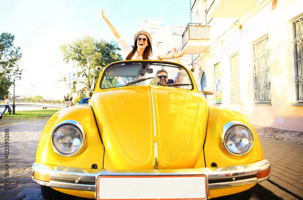 Obraz premium Happy to travel together. Joyful young couple smiling while riding in onvertible