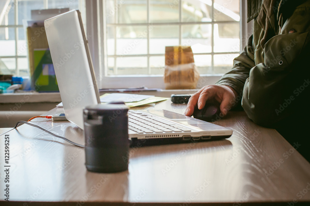 Fototapeta premium adult man with a mustache and glasses, working at a computer, holding a mouse in their hands.