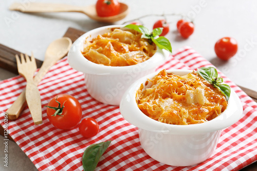 Portions of pasta Al Forno in ceramic bowls on red napkin, closeup