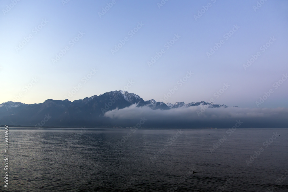  View by a misty morning at sunrise on Lake Geneva, a surreal impression as the alps emerge in the distance in Montreux, Switzerland