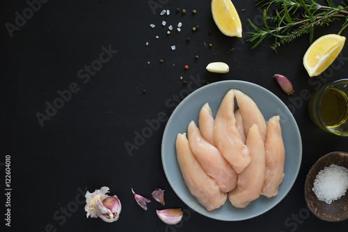 Schilderij op canvas Fresh raw chicken tenders, lemon, garlic, rosemary, olive oil, pepper and salt o