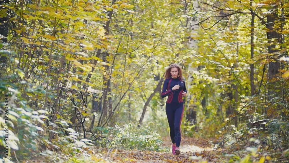 Young runner girl have jogging on autumn road covered with fallen leaves. Sports healthy lifestyle concept, slow motion Young runner girl have jogging on autumn road covered with fallen leaves. Sports healthy lifestyle concept, slow motion