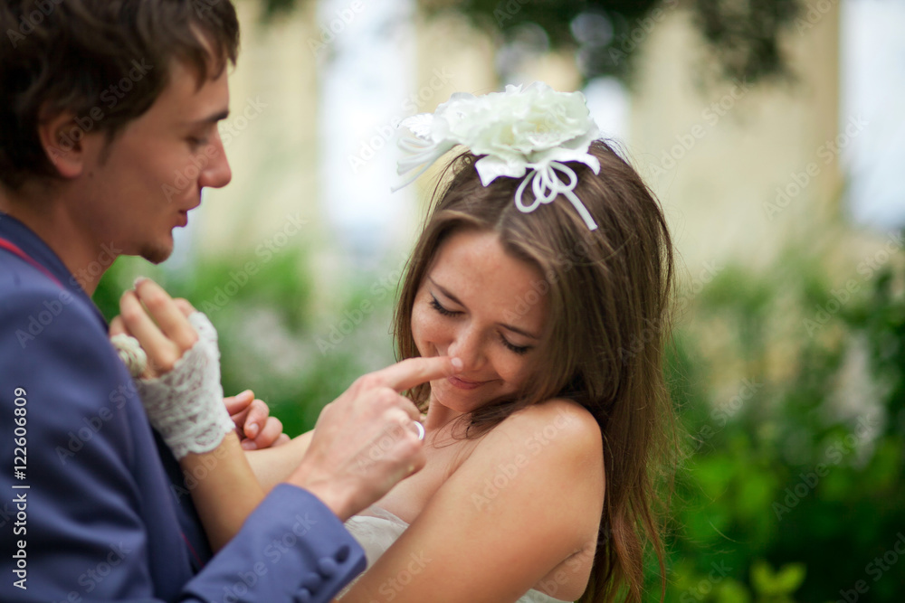Handsome groom touches bride's nose tender while she leans to hi