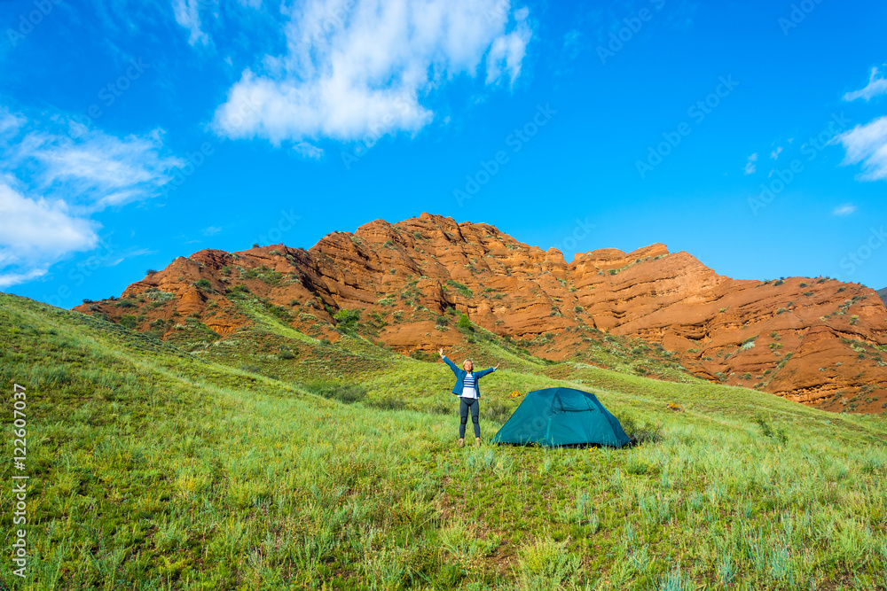 Woman near blue tent on a background of orange mountains, Kyrgyz