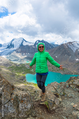 A woman is standing against a background of snow-capped mountain