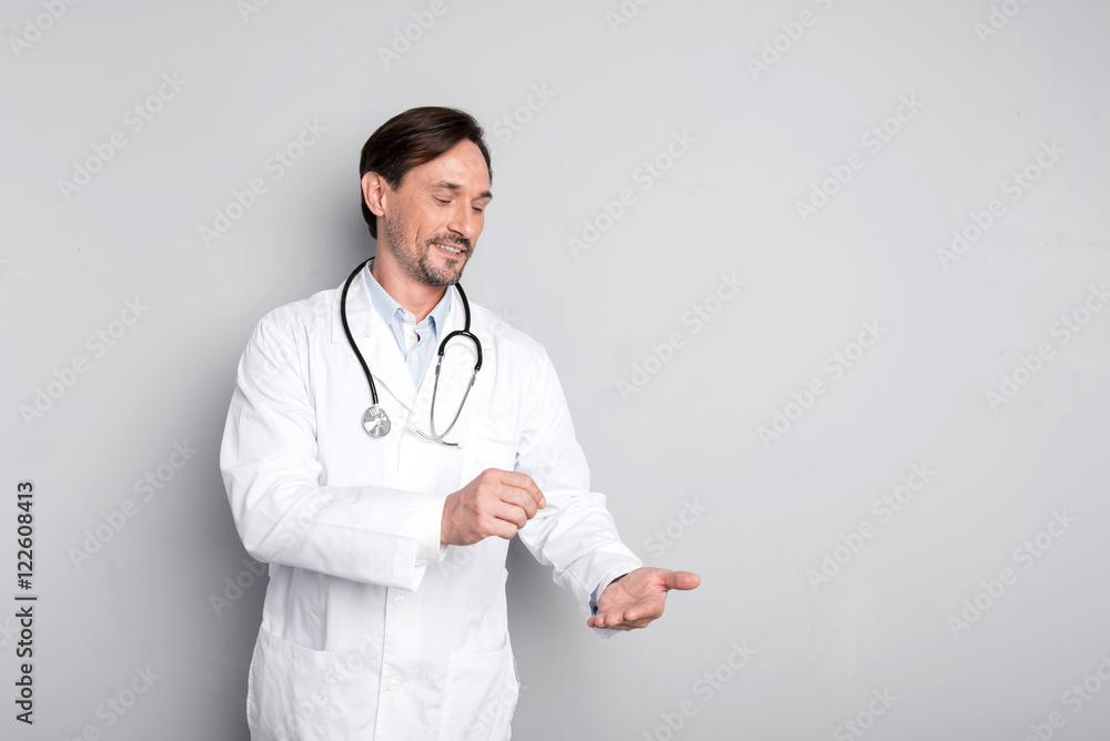Smiling doctor holding a stethoscope and gesturing Smiling doctor holding a stethoscope and gesturing