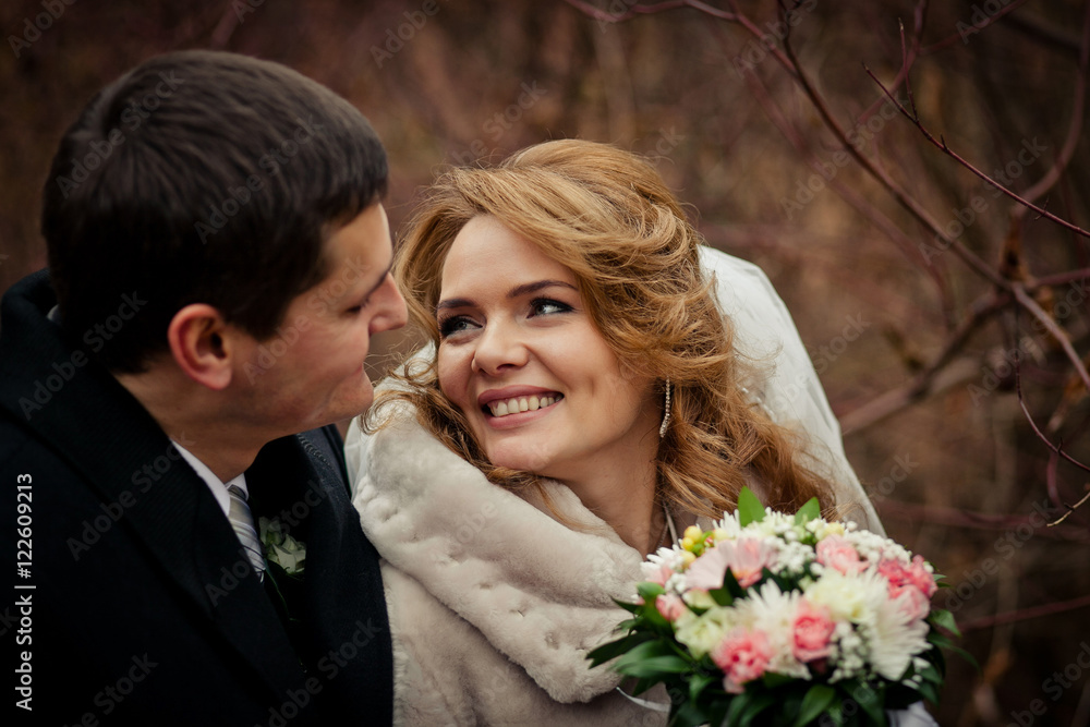 Bride smiles charming while she looks at groom over her shoulder Bride smiles charming while she looks at groom over her shoulder