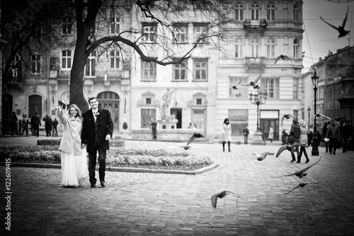Heavenly wedding couple walks through the square while pigeons f