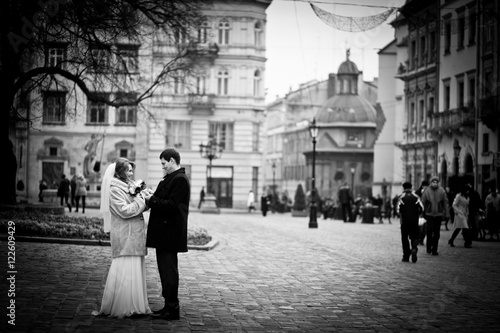 Dreamlike adult wedding couple stands hugging on the square some