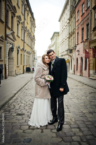 Bride and groom lean to eahc other heads while they stand lonely photo