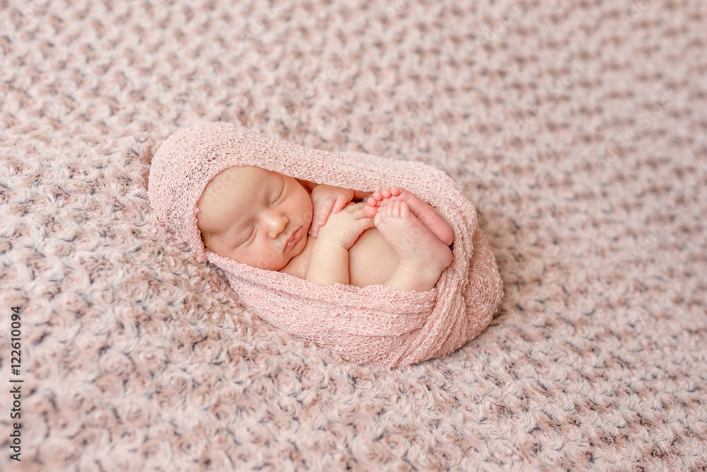 lovely newborn curled up asleep, wrapped in pink diaper