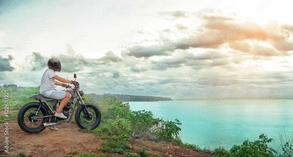 Motorcycler on the top of the mountain over the ocean