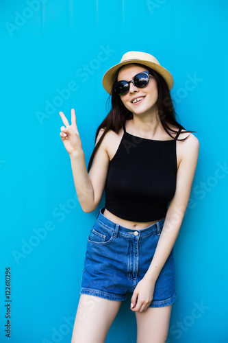 young woman wearing sunglasses in jeans on blue background