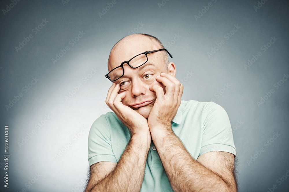Tired middle-aged man suffering fatigue and rubbing his cheek Tired middle-aged man suffering fatigue and rubbing his cheek