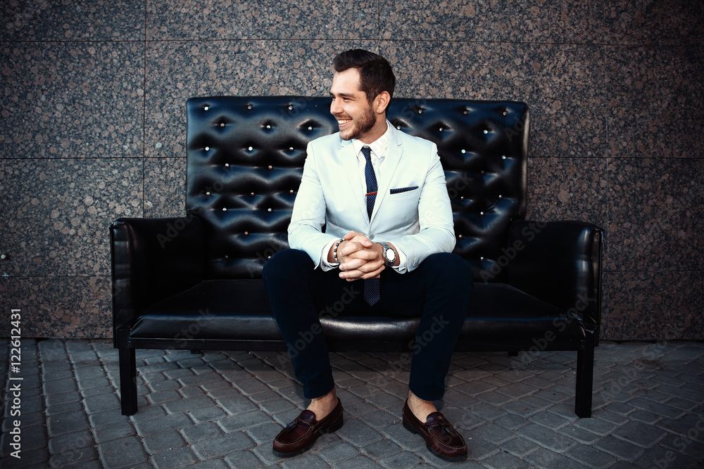 Young handsome bearded stylish man sitting on comfortable leather sofa Young handsome bearded stylish man sitting on comfortable leather sofa
