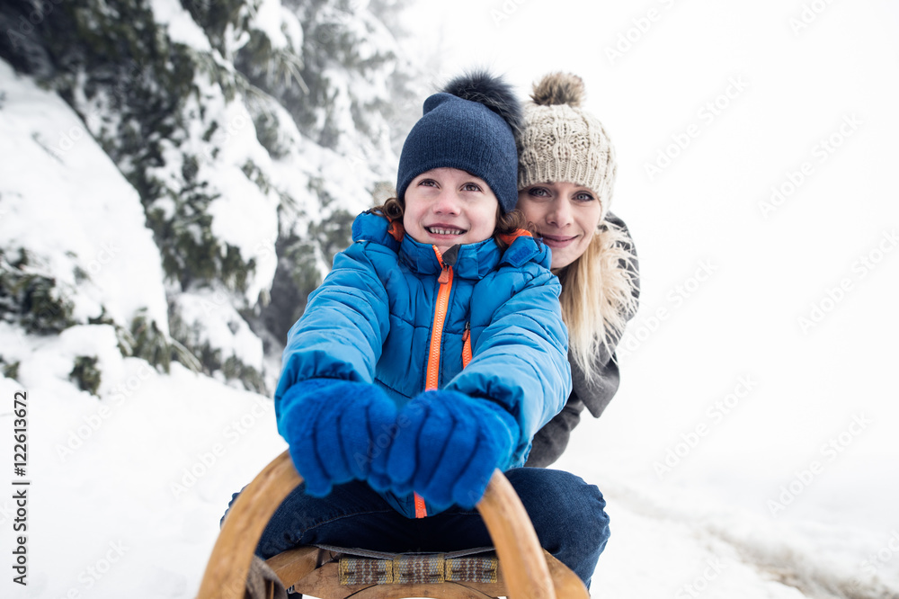Mother with son on sledge. Foggy white winter nature.
