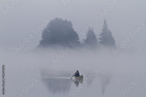 Man paddles solo canoe on Oxtongue Lake, Muskoka, Ontario.