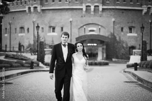 Perfect wedding couple walks along the road from the old fortres