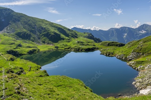 Mountain lake with crystal clear water. Landscape from Capra Lake in Romania and Fagaras mountains in the summer.