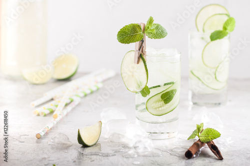 Cold detox cocktail with cucumbers, lime, mint and cinnamon with ice in the glass on the table